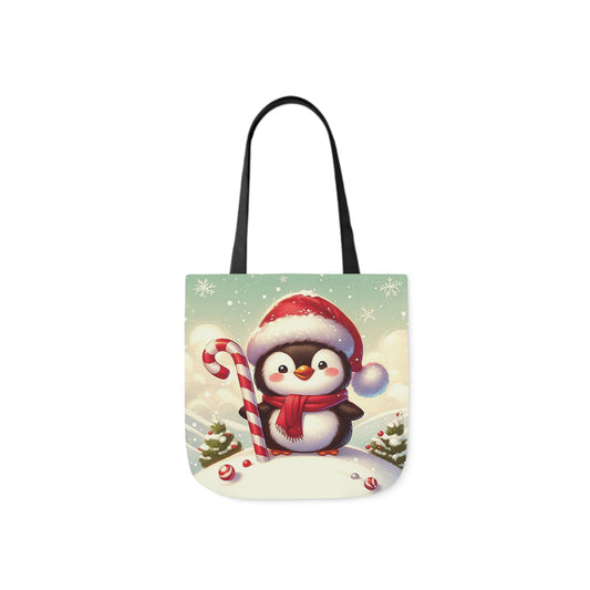 A canvas shoulder tote bag with a design of cute smiling penguin in a Santa hat with a large candy cane.