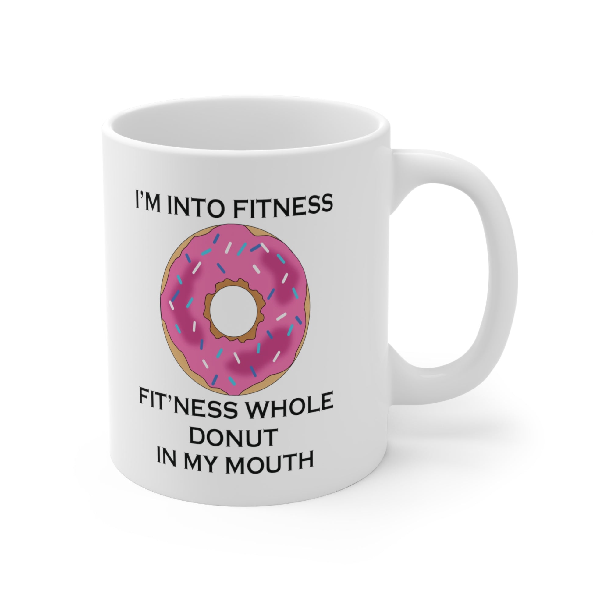 A white ceramic coffee mug with a design of a donut with pink icing and a funny quote: I'm Into Fitness, Fitness Whole Donut In My Mouth