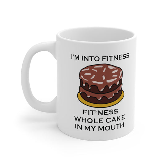 A white ceramic coffee mug with a design of a chocolate cake and the funny quote: I'm Into fitness, Fit'ness Whole Cake In My Mouth