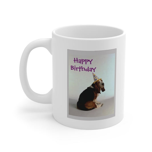 A white ceramic coffee mug with a photo of a Basset dog in a party hat with the quote: Happy Birthday at the top