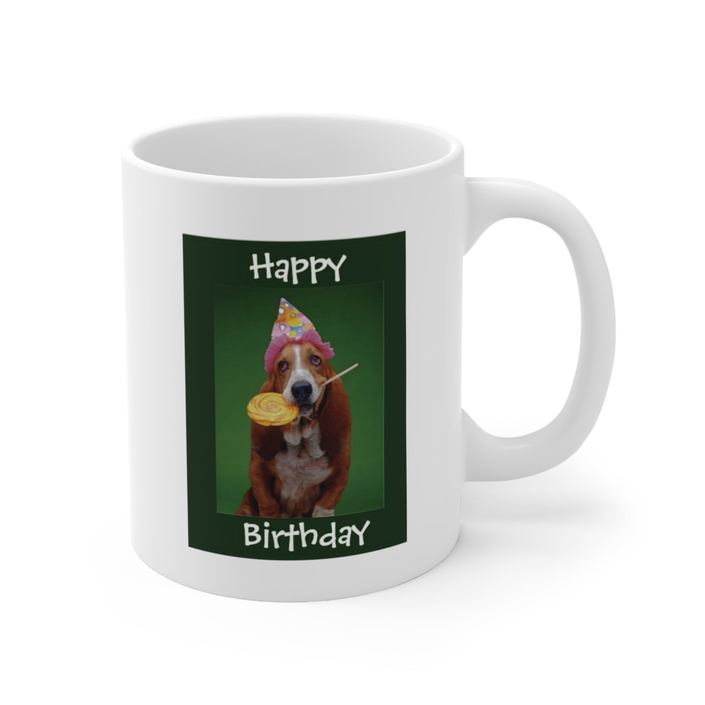 A white ceramic coffee mug with a photo of a Basset hound dog wearing a party hat, with a yellow lollipop in her mouth. The quote reads: Happy Birthday