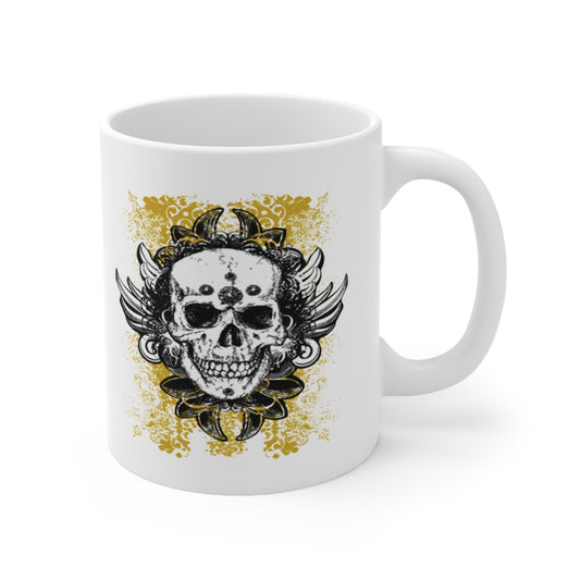 A white ceramic coffee mug with a graffiti design of a vintage grungy skull with wings and a yellow lace background