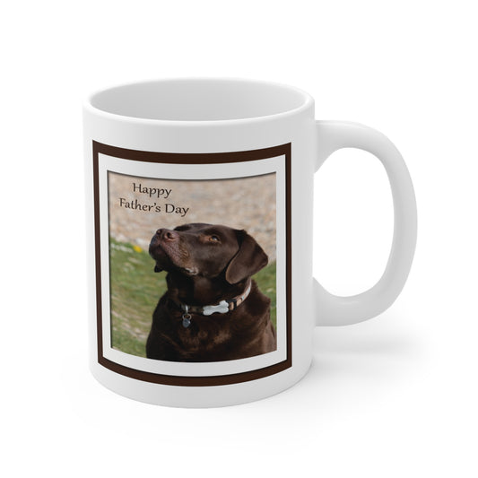 A white ceramic coffee mug with a photo design of a chocolate labrador dog. The dog is looking up at the greeting which reads: Happy Father's Day.