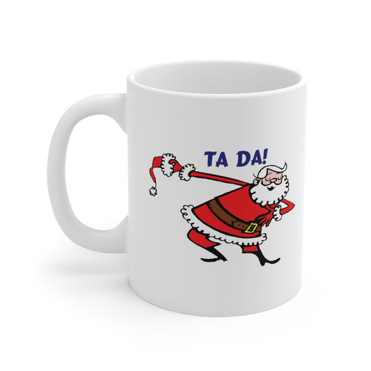 A white ceramic coffee mug with a design of a cartoon Santa Claus taking a bow and saying: Ta Da!