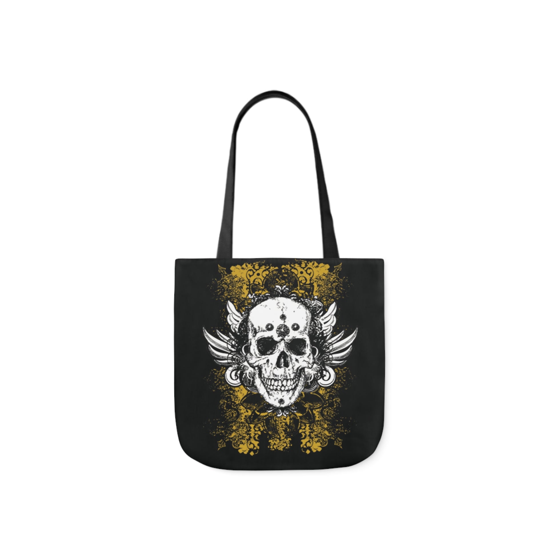 A canvas shoulder tote bag with a design of a vintage grungy black and white skull with wings and decorative yellow lace background graffiti design.