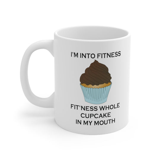 A white ceramic coffee mug with a design of a chocolate cupcake and the funny quote: I'm Into Fitness, Fit'ness Whole Cupcake In My Mouth